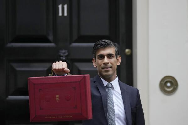 FILE - Britain's Chancellor of the Exchequer Rishi Sunak holds up the traditional ministerial red dispatch box as he leaves for the House of Commons to deliver the Budget in London, Oct. 27, 2021. Revelations that Prime Minister Boris Johnson and his staff partied while Britain was in a coronavirus lockdown have provoked public outrage and led some members of his Conservative Party to consider ousting their leader. If they manage to push Johnson out — or if he resigns — the party would hold a leadership contest to choose his replacement. Sunak, 41, is widely regarded as the brightest rising star in the party, the best known of the contenders to the public — and the bookies’ favorite to succeed Johnson. (AP Photo/Alastair Grant, File)