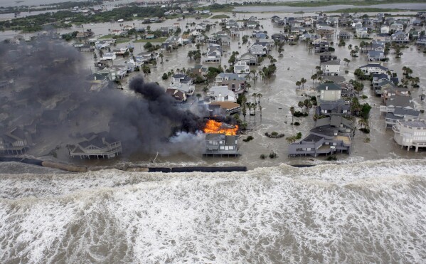 FILE - Fire destroys homes along the beach on Galveston Island, Texas, as Hurricane Ike approaches, Sept. 12, 2008. Hurricanes beginning with the letter "I" have been among the most destructive to strike the United States, moreso than any other letter of the alphabet. Idalia is on a path to strike Florida's Gulf Coast as a major hurricane to join the long list of catastrophic examples. (AP Photo/David J. Phillip, File)