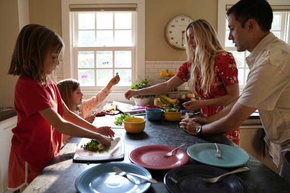 OB-GYN Dr. Kylie Cooper prepares dinner with her husband, Nick, and daughters, Cleo, left, and Hazel, Thursday, June 15, 2023, in Minnesota. After the Supreme Court overturned Roe v. Wade in June 2022, many maternal care doctors in restrictive states face the choice of whether to stay or leave. (AP Photo/Abbie Parr)