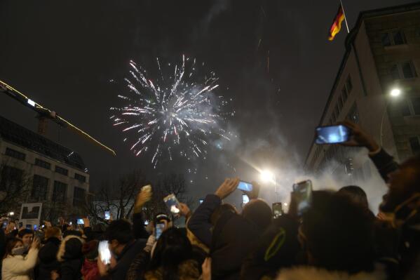 Spectators at the boulevard Unter den Linden watch fireworks as they celebrate the New Year near the Brandenburg Gate in Berlin, Germany, Saturday, Jan. 1, 2022. Large-scale New Year celebrations are prohibited in Germany. (AP Photo/Markus Schreiber)