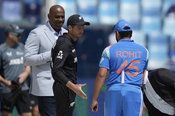 New Zealand's captain Mitch Santner, center, greets India's captain Rohit Sharma after the coin toss ahead of the ICC Champions Trophy cricket match between India and New Zealand at Dubai International Cricket Stadium in Dubai, United Arab Emirates, Sunday, March 2, 2025. (AP Photo/Altaf Qadri)
