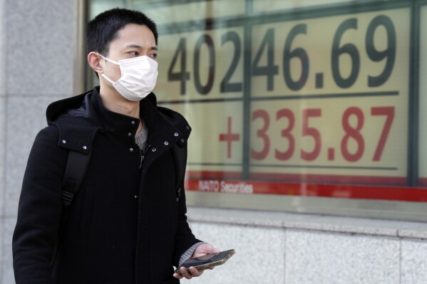 A person walks in front of an electronic stock board showing Japan's Nikkei 225 index at a securities firm Monday, March 4, 2024, in Tokyo. Japan's Nikkei 225 share benchmark has topped 40,000 for the first time as strong demand for technology shares keeps pushing the index higher.(AP Photo/Eugene Hoshiko)