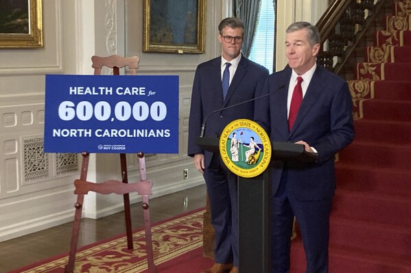 North Carolina Gov. Roy Cooper, right, speaks while state Health and Human Services Secretary Kody Kinsley listens at an Executive Mansion news conference in Raleigh, N.C., on Monday, Sept. 25, 2023. Cooper and Kinsley announced that North Carolina would launch Medicaid expansion coverage on Dec. 1. Expansion will be able to start because Cooper said he'll let a state budget bill sent by the General Assembly last week to his desk become law without his signature. (AP Photo/Gary D. Robertson)