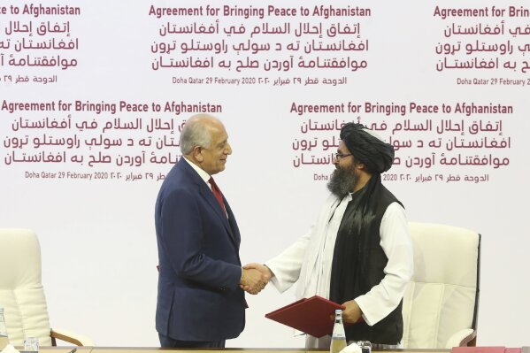 FILE - In this Feb. 29, 2020 file photo, U.S. peace envoy Zalmay Khalilzad, left, and Mullah Abdul Ghani Baradar, the Taliban group's top political leader shake hands after signing a peace agreement between Taliban and U.S. officials in Doha, Qatar. An Afghan official said Thursday, May 14, 2020, that a suicide attack in eastern Afghanistan targeted a military compound but was detonated before it reached the compound killing several civilians and wounding tens of others. The Taliban took responsibility for the bombing calling it retaliation for statements Tuesday by President Ashraf Ghani blaming Taliban for a brutal attack on a maternity hospital that killed tens of people, an attack that the Taliban were quick to condemn. (AP Photo/Hussein Sayed, File)