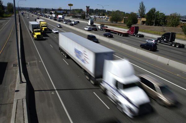 FILE - In this Wednesday, Aug. 24, 2016, file photo, truck and automobile traffic mix on Interstate 5, headed north through Fife, Wash., near the Port of Tacoma. Two U.S. senators have introduced a bill that would electronically limit tractor-trailer speeds to 65 miles per hour, a move they say would save lives on the nation’s highways. Georgia Republican Johnny Isakson and Delaware Democrat Chris Coons introduced the measure Thursday, June 27, 2019.  (AP Photo/Ted S. Warren, File)