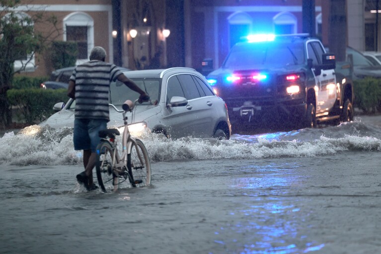 A bicyclist goes through flooded streets on Stirling Road near Federal Highway in Hollywood, Fla., June 12, 2024. (Mike Stocker/South Florida Sun-Sentinel via AP)
