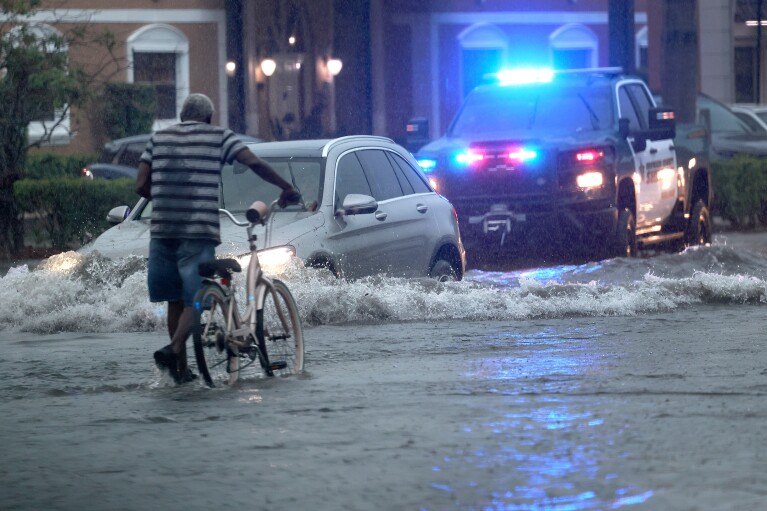 Un ciclista navega por calles inundadas en Stirling Road, cerca de la Carretera Federal en Hollywood, el 12 de junio de 2024.  (Mike Stocker/Sun-Sentinel del Sur de Florida vía AP)