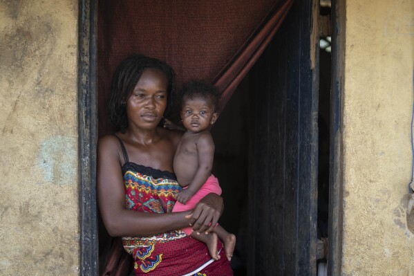 Annie Kopacitino holds her daughter, who she says has been affected by the pollution caused by oil drilling, in her village of Tshiende, Moanda, Democratic Republic of the Congo, Saturday, Dec. 23, 2023. The country is looking to expand the oil drilling. (AP Photo/Mosa'ab Elshamy)