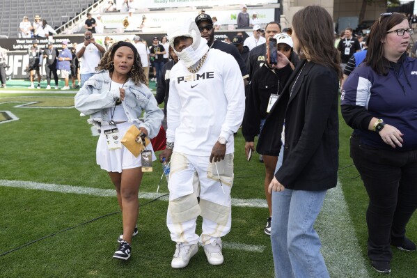 Rap singer DaBaby, center, steps on the gridiron as Colorado warms up before hosting Southern California in an NCAA college football game Saturday, Sept. 30, 2023, in Boulder, Colo. (AP Photo/David Zalubowski)
