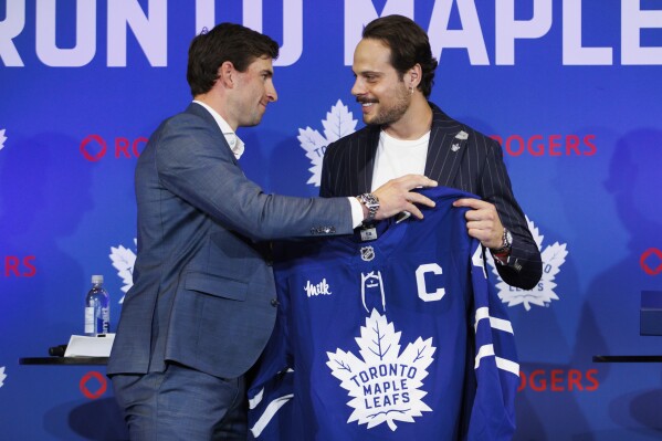 Former Toronto Maple Leafs captain John Tavares, left, hands the captains jersey to Maple Leafs new captain Auston Matthews in Toronto, Wednesday, Aug. 14, 2024. (Cole Burston/The Canadian Press via AP)