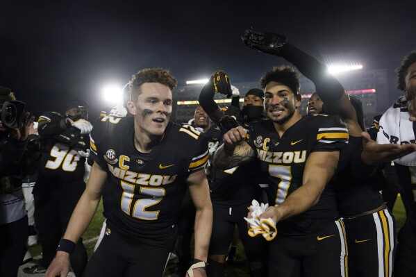 Missouri quarterback Brady Cook (12) and running back Cody Schrader (7) celebrate with teammates following an NCAA college football game against Florida Saturday, Nov. 18, 2023, in Columbia, Mo. Missouri won 33-31. (AP Photo/Jeff Roberson)