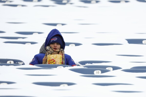 A Buffalo Bills fan sits amongst snow covered seats while waiting for the start an NFL wild-card playoff football game between the Buffalo Bills and the Pittsburgh Steelers, Monday, Jan. 15, 2024, in Buffalo, N.Y. (AP Photo/Jeffrey T. Barnes)