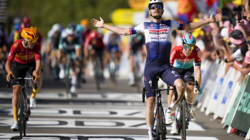 Denmark's Kasper Asgreen celebrates as he crosses the finish line ahead of Netherlands' Pascal Eenkhoorn, right, and Norway's Jonas Abrahamsen, left, to win the eighteenth stage of the Tour de France cycling race over 185 kilometers (115 miles) with start in Moutiers and finish in Bourg-en-Bresse, France, Thursday, July 20, 2023. (AP Photo/Daniel Cole)