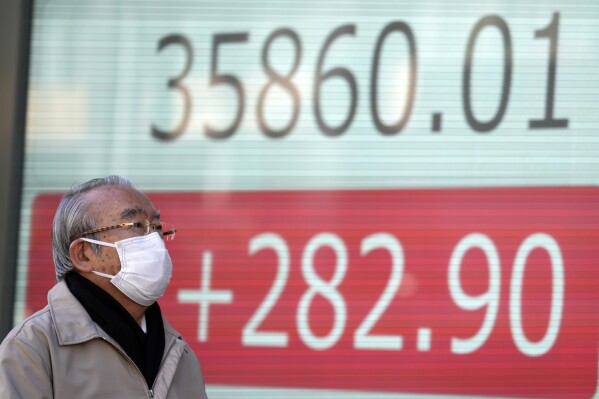 A person walks in front of an electronic stock board showing Japan's Nikkei 225 index at a securities firm Monday, Jan. 15, 2024, in Tokyo. (AP Photo/Eugene Hoshiko)