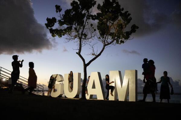 CAPTION CORRECTION CORRECTS DATE: FILE - Tourists pose for photos at a sign along a popular beach in Tamuning, Guam, May 11, 2019. The powerful Pacific typhoon Mawar that lashed of Guam on Thursday, May 25, 2023, with damaging high winds, heavy rains and a dangerous storm surge arrived as the worst storm in decades, interrupting life for residents and the U.S. military on a tropical island that is the easternmost of the nation's territories. (AP Photo/David Goldman, File)