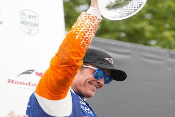 Scott Dixon, of New Zealand, lifts his trophy after winning an IndyCar auto race in Toronto, Sunday, July 17, 2022. (Andrew Lahodynskyj/The Canadian Press via AP)