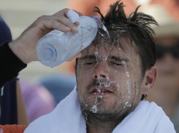 FILE - Stan Wawrinka, of Switzerland, pours water on his face during a changeover in his match against Ugo Humbert, of France, during the second round of the U.S. Open tennis tournament, Aug. 29, 2018, in New York. An Associated Press analysis shows the average high temperatures during the U.S. Open and the three other Grand Slam tennis tournaments steadily have grown hotter and more dangerous in recent decades. (AP Photo/Seth Wenig, File)