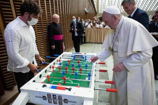 Pope Francis plays with Natale Tonini, president of Sport Toscana Calcio Balilla association, at the end of the weekly general audience, Wednesday, Aug.18. 2021. Francis played a round on the table that was presented to him  by representatives of a the association, that created a special Foosball table designed to be inclusive, for people with physical disabilities, to encourage their participation in sport. (Vatican Media via AP)