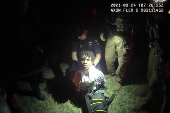 In this image from body camera video provided by Sedgwick County, police put Cedric “C.J.” Lofton, 17, into a body-length restraining device called a WRAP outside his home in Wichita, Kan., on Sept. 24, 2021. His foster father, unable to deal with a teen who seemed to be in the throes of schizophrenia, had called Wichita police. When they arrived, Cedric refused to leave the porch and go with them; he was obstinate but afraid, meek but frantic. (Sedgwick County via AP)