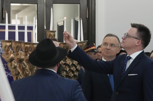 President Andrzej Duda, second right, Speaker of the Polish Parliament Szymon Holownia, right, and the Polish Jewish community come together on the last night of Hanukkah for a candle lighting ceremony in parliament, in Warsaw, Poland, Thursday Dec. 14, 2023. The ceremony was held to send a message of tolerance and to denounce antisemitism after a far-right lawmaker used a fire extinguisher to put out burning candles on a menorah. the Polish Jewish community come together on the last night of Hanukkah for a candle lighting ceremony in parliament, in Warsaw, Poland, on Thursday Dec. 14, 2023. The ceremony was held to send a message of tolerance and to denounce antisemitism after a far-right lawmaker used a fire extinguisher to put out burning candles on a menorah. (AP Photo/Czarek Sokolowski)