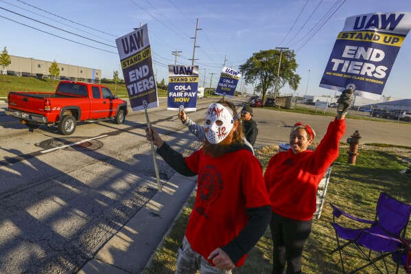 UAW members including Scott Kralovic, wearing a mask, work the picket line during a strike Tuesday, Sept. 19, 2023, at the Stellantis Toledo Assembly Complex where Jeeps are made in Toledo, Ohio. (Jeremy Wadsworth/The Blade via AP)
