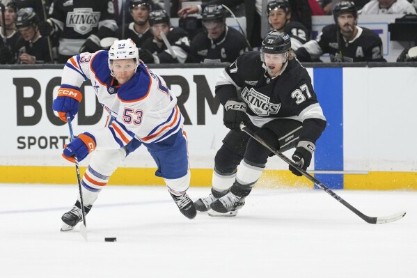 Edmonton Oilers center Jeff Skinner, left, moves the puck while under pressure from Los Angeles Kings left wing Warren Foegele during the first period in Game 1 of an NHL hockey first-round playoff series Monday, April 21, 2025, in Los Angeles. (AP Photo/Mark J. Terrill)