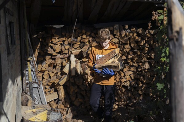 Artem Yarema, de 13 años, carga leña cerca de la casa de su familia en Moshchun, cerca de Kiev, Ucrania, el martes 10 de octubre de 2023. Muchos ucranianos esperan lo mismo o peor el próximo invierno y han pasado meses preparándose, incluida la recolección de leña y la compra de generadores. . (Foto AP/Alex Babenko)