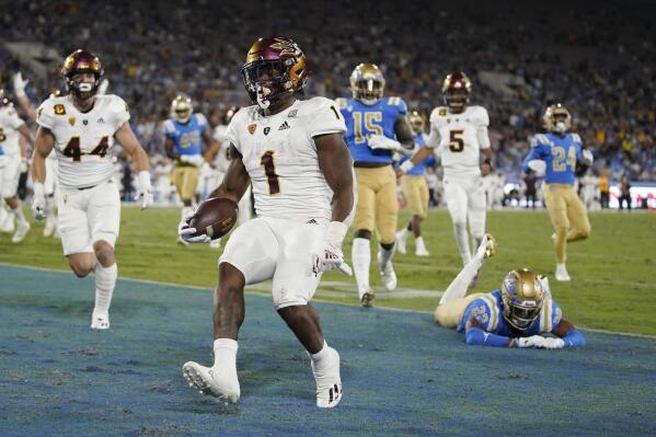 Arizona State running back DeaMonte Trayanum, center, runs the ball in for a touchdown as UCLA defensive back Obi Eboh, lower right, falls during the first half of an NCAA college football game Saturday, Oct. 2, 2021, in Pasadena, Calif. (AP Photo/Mark J. Terrill)