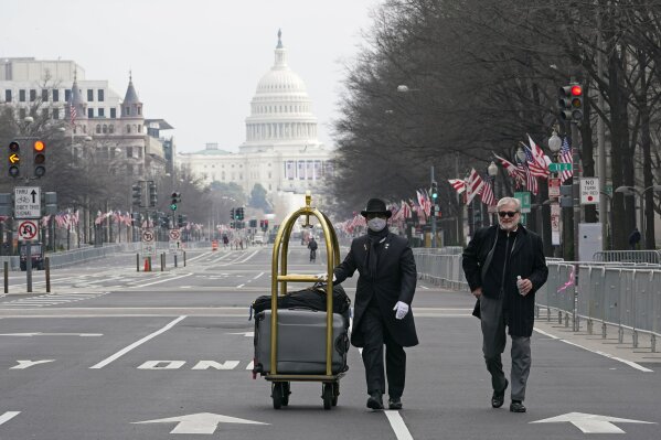 Danish Rozario, left, of Silver Spring, Md., wheels the baggage down Pennsylvania Avenue for a guest at the Trump Hotel in Washington, Friday, Jan. 15, 2021, ahead of the inauguration of President-elect Joe Biden and Vice President-elect Kamala Harris.Between the still-raging pandemic and suddenly very real threat of violence from supporters of outgoing President Donald Trump, Jan. 20 promises to be one of the most unusual presidential inaugurations in American history. Joe Biden and Kamala Harris will take the oath of office outside the Capitol.  (AP Photo/Susan Walsh)
