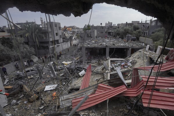Palestinians inspect the rubble of a building of the Al Nawasrah family destroyed in an Israeli strike in Maghazi refugee camp, central Gaza Strip, Monday, Dec. 25, 2023. (AP Photo/Adel Hana)