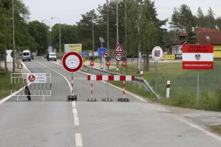 FILE - In this May 13, 2020 file photo, a barrier blocks the road at the closed border crossing from Austria to the Czech Republic near Reinthal, Austria. European Union countries are set to adopt a common traffic light system to coordinate traveling across the 27-nation bloc, but a return to a full freedom of movement in the midst of the COVID-19 pandemic remains far from reach. (AP Photo/Ronald Zak, File)