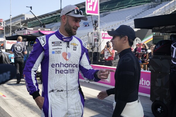 FILE - Shane van Gisbergen, left, and Kamui Kobayashi talk before a practice session for the NASCAR Cup Series auto race at Indianapolis Motor Speedway, Saturday, Aug. 12, 2023, in Indianapolis. New Zealand race car driver Shane van Gisbergen will leave Australia at the end of the V8 Supercars season and move to the United States to run a developmental NASCAR schedule with Trackhouse Racing. (AP Photo/Darron Cummings, File)