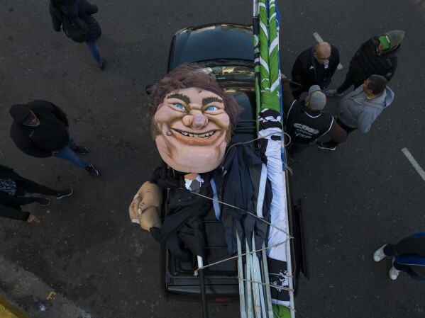 A large puppet in the likeness of Argentine President Javier Milei lays in the back of a truck after being paraded at a protest demanding work opportunities, from San Cayetano church to the Government House, in downtown Buenos Aires, Argentina, Wednesday, Aug. 7, 2024, the feast day of St. Cajetan, known as the patron of the unemployed. (AP Photo/Rodrigo Abd)