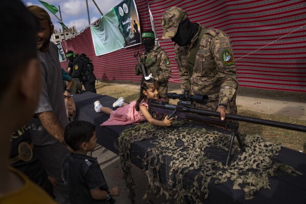 A Palestinian child poses with a weapon at an arms show by Hamas group's military wing at Nusseirat refugee camp, central Gaza Strip, Friday, June 30, 2023. (AP Photo/Fatima Shbair)
