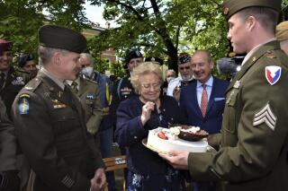 Soldiers from U.S. Army Garrison Italy return a birthday cake to Meri Mion, center, in Vicenza, northern Italy, Thursday, April 28, 2022, to replace the one U.S. soldiers ate as they entered her hometown during one of the final battles of World War II. Meri Mion, who turns 90 on Friday, wiped away tears as she was presented with the cake. Mion was a 13-year-old when Americans came to her nearby village, San Pietro in Gù. (Laura Krieder, U.S. Army via AP)