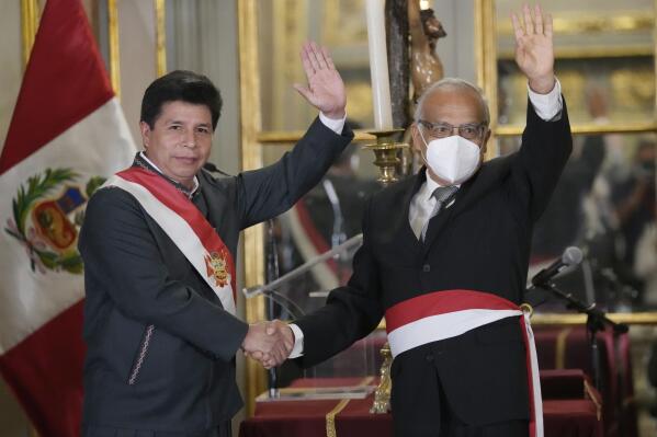 Peru's President Pedro Castillo, left, waves alongside his new Cabinet Chief Anibal Torres, during the swearing-in of Castillos´s new Cabinet, at the government palace in Lima, Peru, Tuesday, Feb. 8, 2022. This is Castillo's fourth Cabinet shakeup in six months. (AP Photo/Martin Mejia)