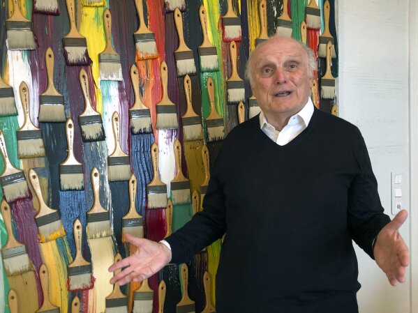 In this photo taken on Monday, March 2, 2020, billionaire art dealer David Nahmad poses in front of a colorful work by French-born American artist Arman, in Nahmad's home in Monaco. Nahmad has spent decades accumulating what he believes is now the world's largest private collection of works by Pablo Picasso, but he is about to part with one of them. A still life that Picasso painted in 1921 is being raffled off for charity in Paris this month with tickets at 100 euros each. (AP Photo/John Leicester)