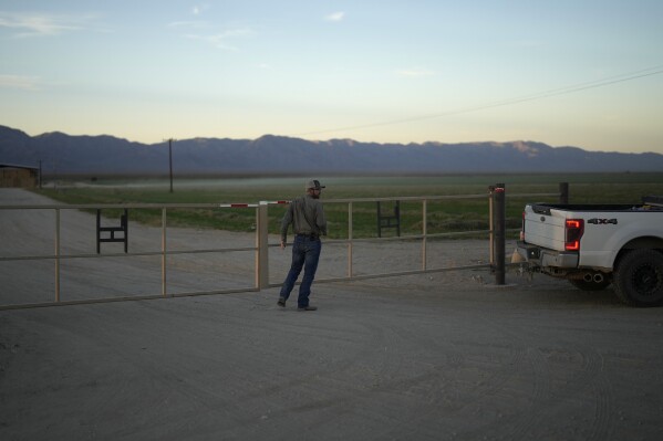 Farmer Matthew Hancock closes a gate at his farm Tuesday, Oct. 17, 2023, in the McMullen Valley in Wenden, Ariz. Hancock is concerned that state officials could be eyeing groundwater from the McMullen Valley for Phoenix's future needs amid shortages in Colorado River water. (AP Photo/John Locher)
