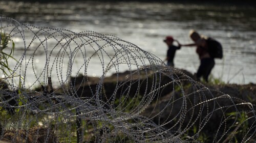 Migrants walk along concertina wire as they try to cross the Rio Grande at the Texas-U.S. border in Eagle Pass, Texas, Thursday, July 6, 2023. (AP Photo/Eric Gay)