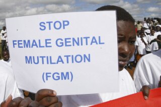 FILE - In this April 21, 2007 file photo, a Masai girl holds a protest sign during the anti-female genital mutilation (FGM) protest in Kilgoris, Kenya. The World Health Organization says the practice constitutes an "extreme form of discrimination" against women. Nearly always carried out on minors, it can result in excessive bleeding and death or cause problems including infections, complications in childbirth and depression. (AP Photo/Sayyid Azim, File)