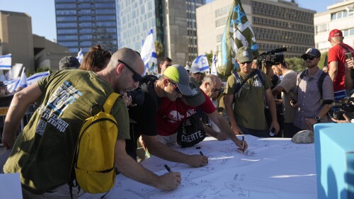 Israeli military reservists sign a declaration of refusal to report for duty to protest against plans by Prime Minister Benjamin Netanyahu's government to overhaul the judicial system, in Tel Aviv, Israel, Wednesday, July 19, 2023. Divisions over the contentious government plan have infiltrated the country's military, where reservists in key units have pledged not to show up for duty if the legislative changes are approved. (AP Photo/Ohad Zwigenberg)