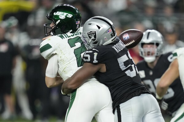New York Jets quarterback Zach Wilson, right, fumbles as he is hit by Las Vegas Raiders defensive end Malcolm Koonce (51) during the second half of an NFL football game Sunday, Nov. 12, 2023, in Las Vegas. The Jets recovered the ball. (AP Photo/John Locher)