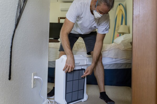 Daniel Skousen shows the filter of an air purifier he uses after deep cleaning his neighbor's unit on Friday, Nov. 3, 2023, in Lahaina, Hawaii. (AP Photo/Mengshin Lin)