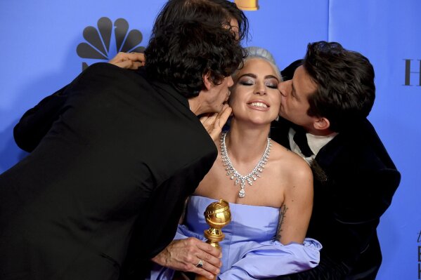 
              Anthony Rossomando, from left, Andrew Wyatt, and Mark Ronson, right, kiss Lady Gaga, second right, as they pose in the press room with the award for best original song, motion picture for "Shallow" from the film "A Star Is Born" at the 76th annual Golden Globe Awards at the Beverly Hilton Hotel on Sunday, Jan. 6, 2019, in Beverly Hills, Calif. (Photo by Jordan Strauss/Invision/AP)
            