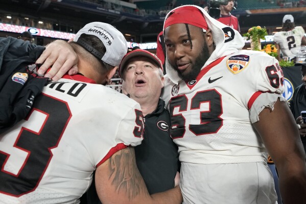 Georgia head coach Kirby Smart, center, hugs offensive lineman Dylan Fairchild, left, and offensive lineman Sedrick Van Pran (63) after the Orange Bowl NCAA college football game against Florida State, Saturday, Dec. 30, 2023, in Miami Gardens, Fla. (AP Photo/Lynne Sladky)