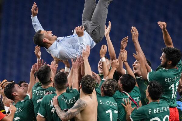 Players of Mexico lift coach Jaime Lozano to celebrate beating 3-1 Japan in the men's bronze medal soccer match at the 2020 Summer Olympics, Friday, Aug. 6, 2021, in Saitama, Japan. (AP Photo/Martin Mejia)