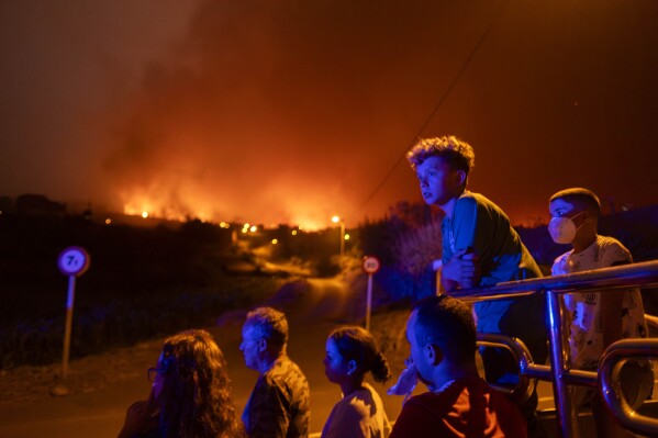 Local residents try to reach their houses in Benijos village as police block the area as fire advances in La Orotava in Tenerife, Canary Islands, Spain, Aug. 19, 2023. (AP Photo/Arturo Rodriguez)