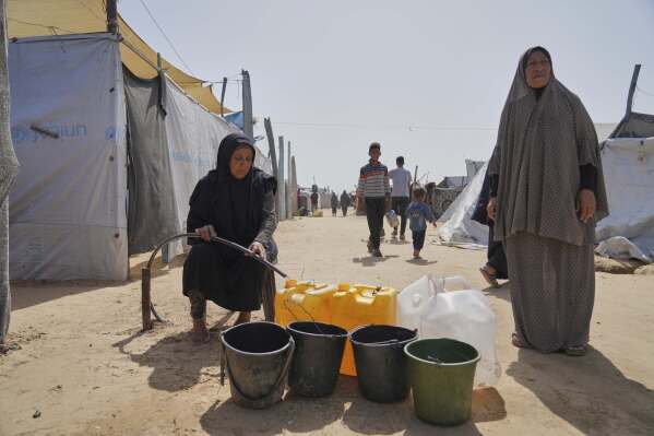 Displaced Palestinians fill jerrycans with water from a pipe at a tent camp in Khan Younis, Gaza Strip, on Sunday, May 11, 2025. (AP Photo/Abdel Kareem Hana)