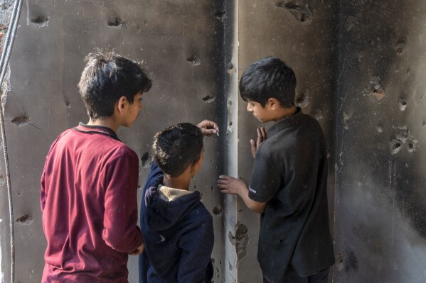 A Kashmiri boy, center, takes out a bullet from the wall of a damaged house after a gunbattle in Kulgam south of Srinagar, Indian controlled Kashmir, Friday, Nov. 17, 2023. Police in Indian-controlled Kashmir said government forces killed five suspected militants in a gunbattle on Thursday. (AP Photo/Dar Yasin)