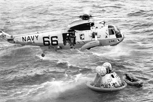 In this July 24, 1969 photo from the U.S. Navy, Navy UDT swimmer Clancy Hatleberg prepares to jump from a helicopter into the water next to the Apollo 11 capsule after it splashed down in the Pacific Ocean, to assist the astronauts into the raft at right. (Milt Putnam/U.S. Navy via ĢӰԺ)